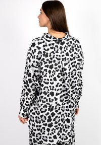 Langärmliges Hemd mit einem Schwarz-Weiß-Leopardenmuster, hergestellt aus glattem Stoff, mit einem kragenähnlichen Ausschnitt und einer lockeren Passform.
