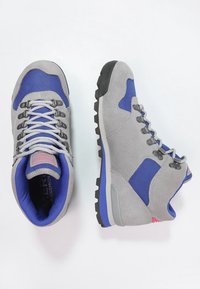 Bottes de randonnée en daim gris avec des accents bleus, tissu texturé, semelles en caoutchouc noir et œillets métalliques pour les lacets. Cheville et languette rembourrées.