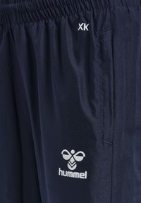 Marineblaue Sportshorts aus leichtem Material. Mit einem elastischen Bund, Seitentaschen und einem weißen Logo mit einem Bienenmotiv.