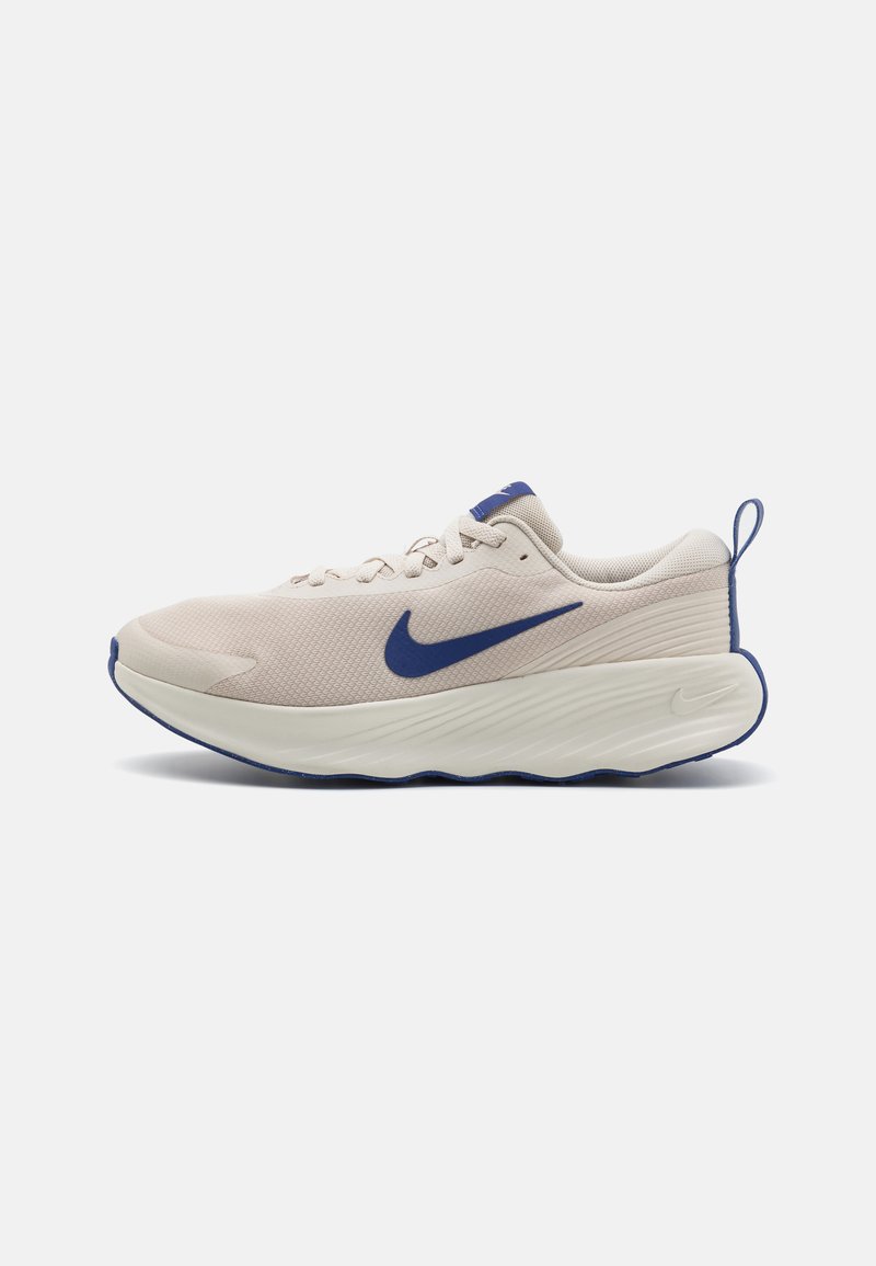 Chaussure de sport beige avec un dessus en maille Texturée, accents bleus et une semelle blanche épaisse avec des rainures pour l'adhérence.