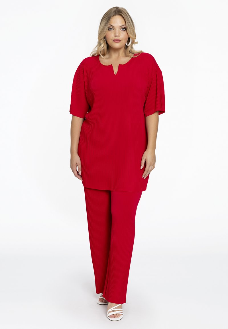 Rode geribbelde top met een keyhole halslijn gecombineerd met bijpassende geribbelde broek. Het ontwerp heeft een losvallende pasvorm en korte mouwen.