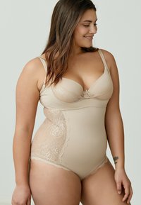 Body shaper beige con dettagli in pizzo floreale sui lati, coppe modellate, spalline regolabili e texture liscia.