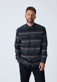 Camicia di flanella a maniche lunghe in blu scuro con strisce orizzontali rosse e grigie. Presenta un colletto con bottoni e tasche frontali. Tessuto morbido.