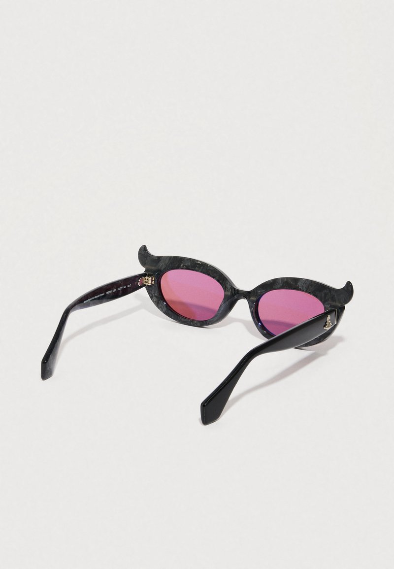 Black sunglasses with pink lenses, featuring a unique cat-eye shape and small decorative accents on the frame. Smooth plastic texture.