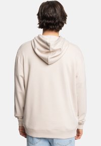 Beige hoodie with a large, soft hood, ribbed cuffs, and bottom hem, featuring a smooth texture and relaxed fit.