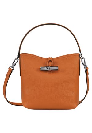 Taske i tanfarvet læder med struktureret finish, metal-lukning med drejeknap, enkelt håndtag øverst samt aftagelig skulderrem med metal-låse.