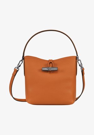 Sac à main en cuir tan avec une finition texturée, fermeture à bascule en métal, une seule poignée supérieure, et une bandoulière amovible avec des attaches en métal.