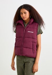Burgundy puffer vest with a high collar, zip closure, front pockets, and "SANTA CRUZ" logo in white on the chest. Smooth, insulated fabric.