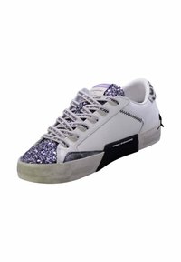Zapatilla blanca con punta de metalizada plateada brillante, acentos negros texturizados y cordones decorados. Presenta una parte superior lisa y un diseño de punta redonda.