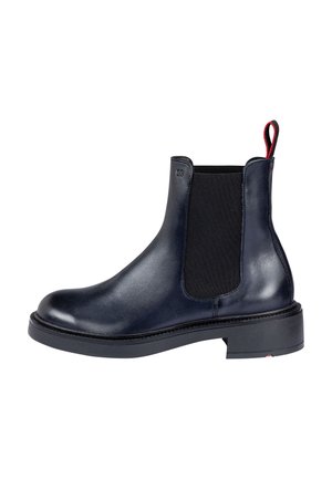 Bottine noire en cuir avec panneau latéral élastique, semelle épaisse et languette rouge à l'arrière.