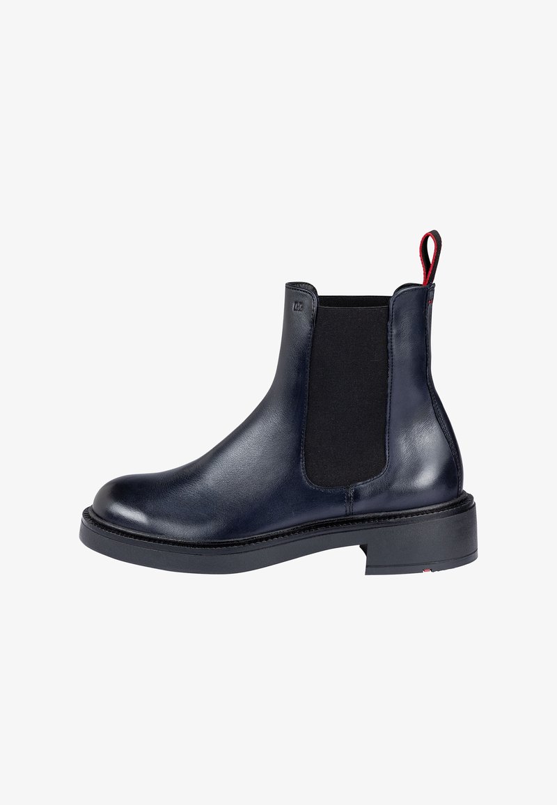 Bottine noire en cuir avec panneau latéral élastique, semelle épaisse et languette rouge à l'arrière.