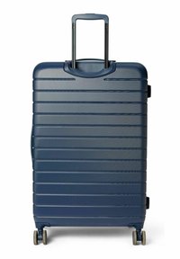 Valise rigide bleu marine avec rainures horizontales, poignée extensible et quatre roues pour la mobilité. Comprend une poignée supérieure pour le transport.