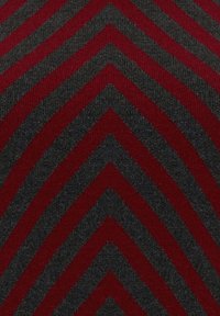 Motif chevron avec des rayures alternées en tissu texturé gris foncé et rouge profond formant une forme en V.