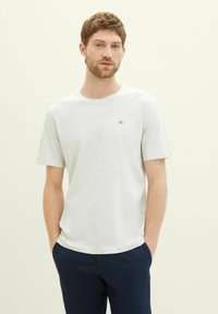 Lys grå kortærmet t-shirt lavet af blødt stof. Har en rund halsudskæring og et lille logo på venstre bryst. Simpelt design.