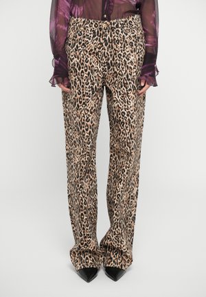 Pantalones de leopardo en beige y negro con un diseño de pierna recta, hechos de tela ligera, acompañados de zapatos negros de punta.