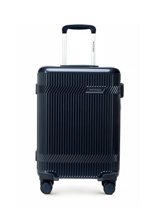 Kompaktowa, ciemnoniebieska walizka z twardą skorupą z pionowymi żebrowaniami, wysuwanym uchwytem, czterema obrotowymi kółkami i widoczną etykietą marki "WITTCHEN".