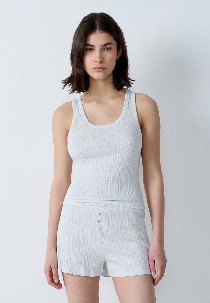 Set di canotta grigia chiara a costine e pantaloni corti, realizzato in tessuto morbido con tre bottoni decorativi sui pantaloni. Design semplice e aderente.