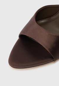 Καφέ σατέν ανοικτού τύπου παπούτσι με φαρδύ λουρί στο πάνω μέρος. Σχεδίαση με μυτερή μύτη και λεία υφή χωρίς πρόσθετες διακοσμήσεις.