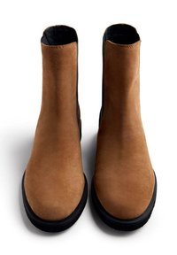Botas de tobillo de ante marrón con un acabado suave, que cuentan con paneles laterales elásticos negros y una suela plana de goma negra.