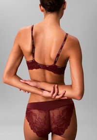 Burgunder Spitze-BH mit verstellbaren Trägern und Schleifenverschluss; passende Bikinihose mit floralen Spitzenakzenten und glattem Bund, beide zeigen komplexe Muster.