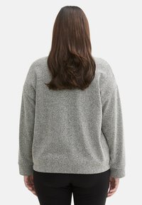 Harmaa herringbone-kuosiset neulepaita, jossa on rento istuvuus, laskeutuvat olkapäät ja pitkät hihat. Sujuva pinta, takaosan näkymä esitetty.