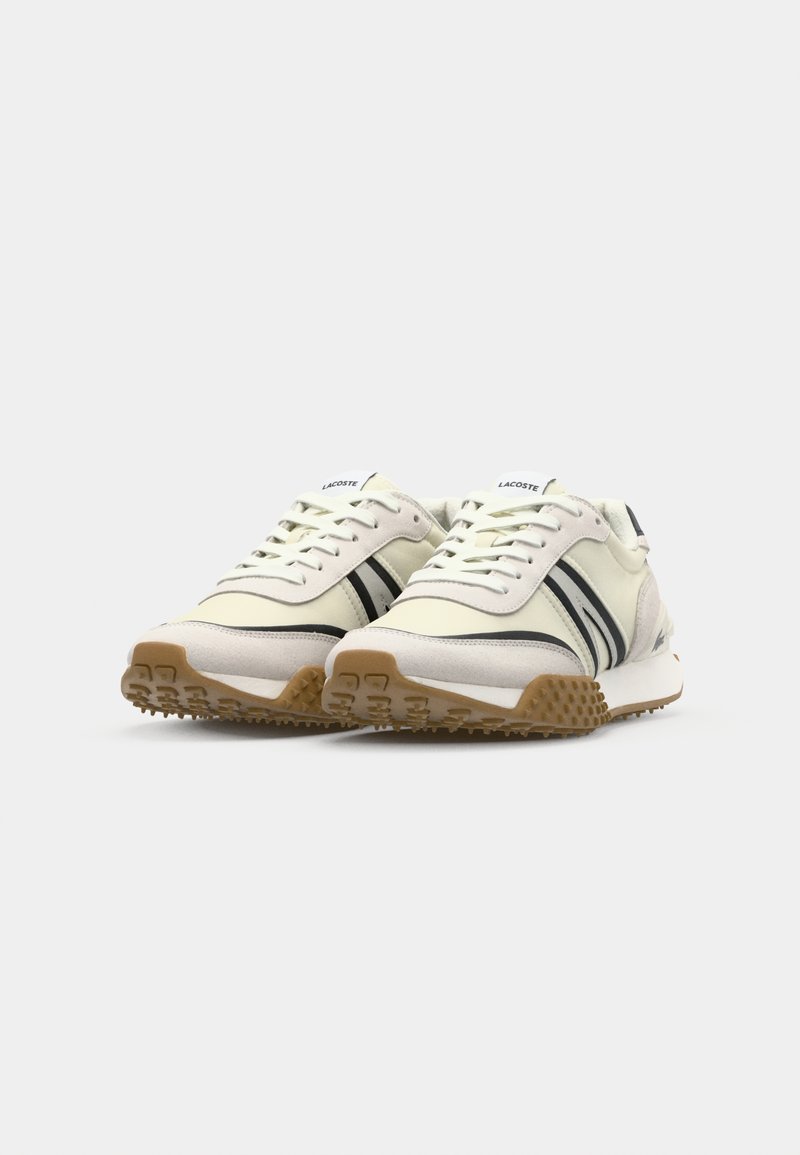 Chaussure en matériaux blancs cassé et gris avec des rayures noires, bout rond, lacets et semelle en caoutchouc texturé de couleur gomme. Logo sur la languette.