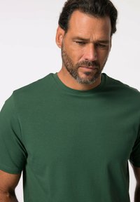 T-shirt verde a collo rotondo realizzato in tessuto morbido, con maniche corte e design semplice, arricchito da sottili dettagli di cucitura.