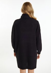 Vestito maglione nero in maglia con colletto alto, maniche lunghe, motivo testurizzato e orlo a coste, progettato per una vestibilità ampia e rilassata.
