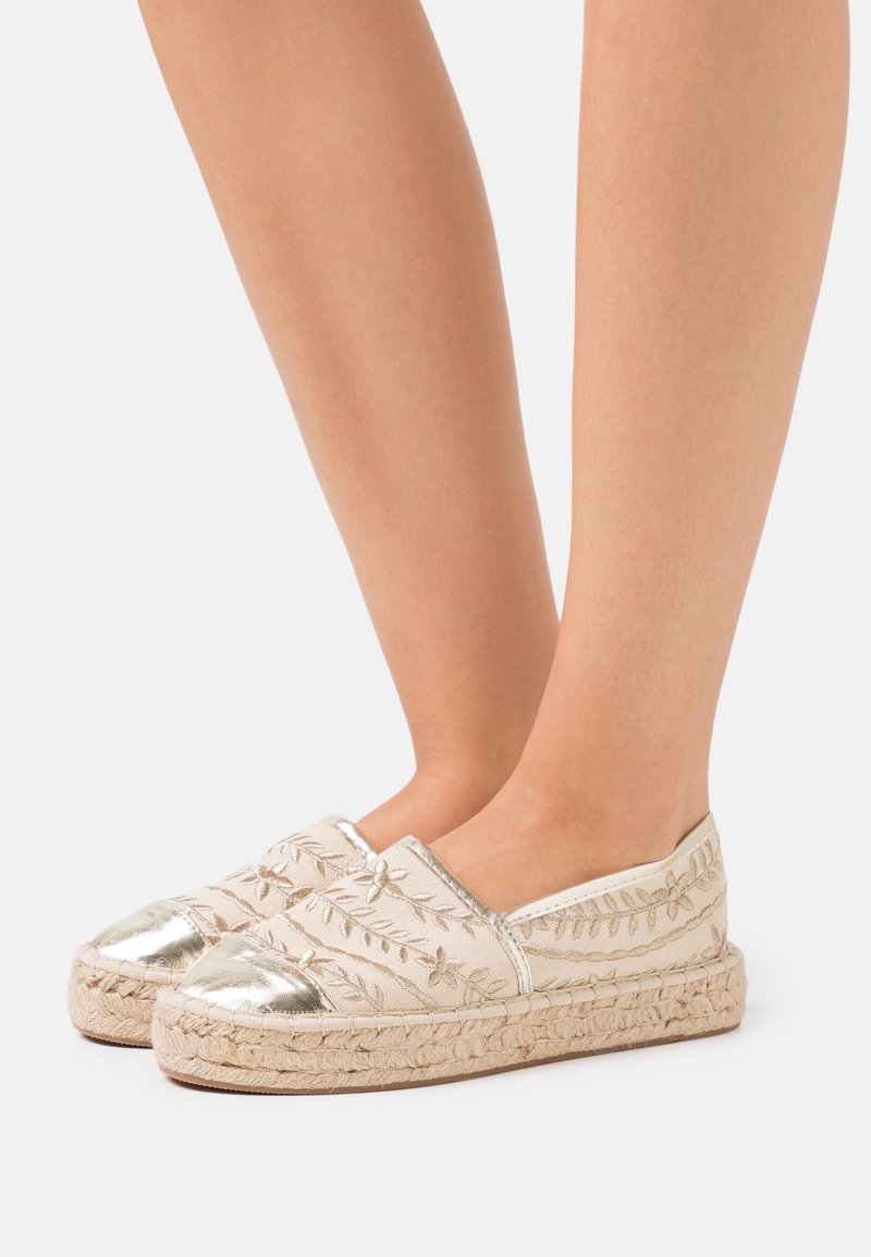 Espadrilles beige con punte metalliche argento, motivi floreali ricamati, suole in corda di juta e design slip-on.