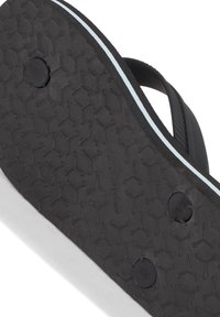 Svartgummi flip-flop-sula med texturerat greppmönster, med en ljusblå accentrand längs kanten och två cirkulära svarta insatser.