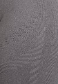Grau gestricktes Kleidungsstück mit einem strukturierten Muster aus diagonalen Streifen und gerippten Abschnitten, das einen glatten und dehnbaren Stoff präsentiert.