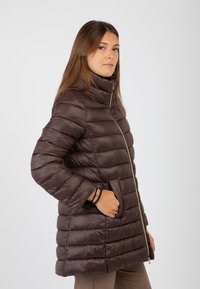 Giubbotto imbottito marrone con collo alto, chiusura a zip e cuciture verticali. Dotato di tasche laterali e una texture liscia e lucida.