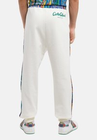Witte sweatpants met kleurrijke, patroon zijpanelen, ribbelboorden en een logo op de tailleband. Soepele textuur, losse pasvorm.