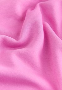 Tissu rose doux avec une texture fine en maille visible et des plis doux créant des ombres et des reflets.