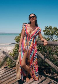Coprispalle da spiaggia a righe multicolori con scollatura a V profonda e vita regolabile con cordoncino, con maniche svasate e un design fluido. Borsa a tracolla intrecciata.