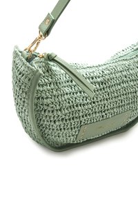 Bolso tejido verde con superficie texturizada, que presenta detalles de cuero a juego, herrajes dorados y cierre con cremallera. Diseño compacto y curvado.