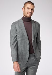 Grau karierter Anzug mit zwei Knöpfen, Reverskragen, Seitentaschen und braunem Rollkragenpullover. Der Stoff wirkt glatt und hat eine strukturierte Passform.