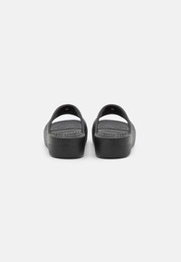 Sandales noires avec une finition lisse et mate, dotées de deux larges sangles et d'une semelle intérieure texturée, conçues pour le confort et la stabilité.
