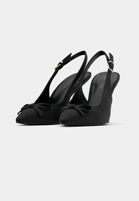 Black slingback heels with pointed toes, small bows on front, and gold buckle straps, shown against a plain white background.