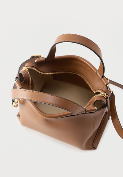 Barna bőrből készült kézitáska arany cipzárral, két fogóval, és tágas, üres belsővel, felülről fehér háttéren.