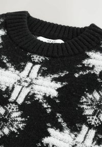 Pull noir avec un motif de flocon de neige blanc, encolure côtelée et texture duveteuse. Le tissu semble chaud et confortable, mettant en avant un design de fête distinct.