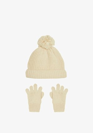 Kreminė mezginio kepurė su pom-pomu viršuje, derinama su atitinkamomis pirštinėmis be pirštų. Savybės: banguota tekstūra ir minkšta medžiaga.