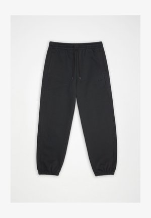 Fekete elasztikus derekú melegítőnadrág húzózsinórral, oldalzsebekkel, rugalmas mandzsettákkal és finom "HANS" logóval a bal combon, fehér háttéren lefektetve.