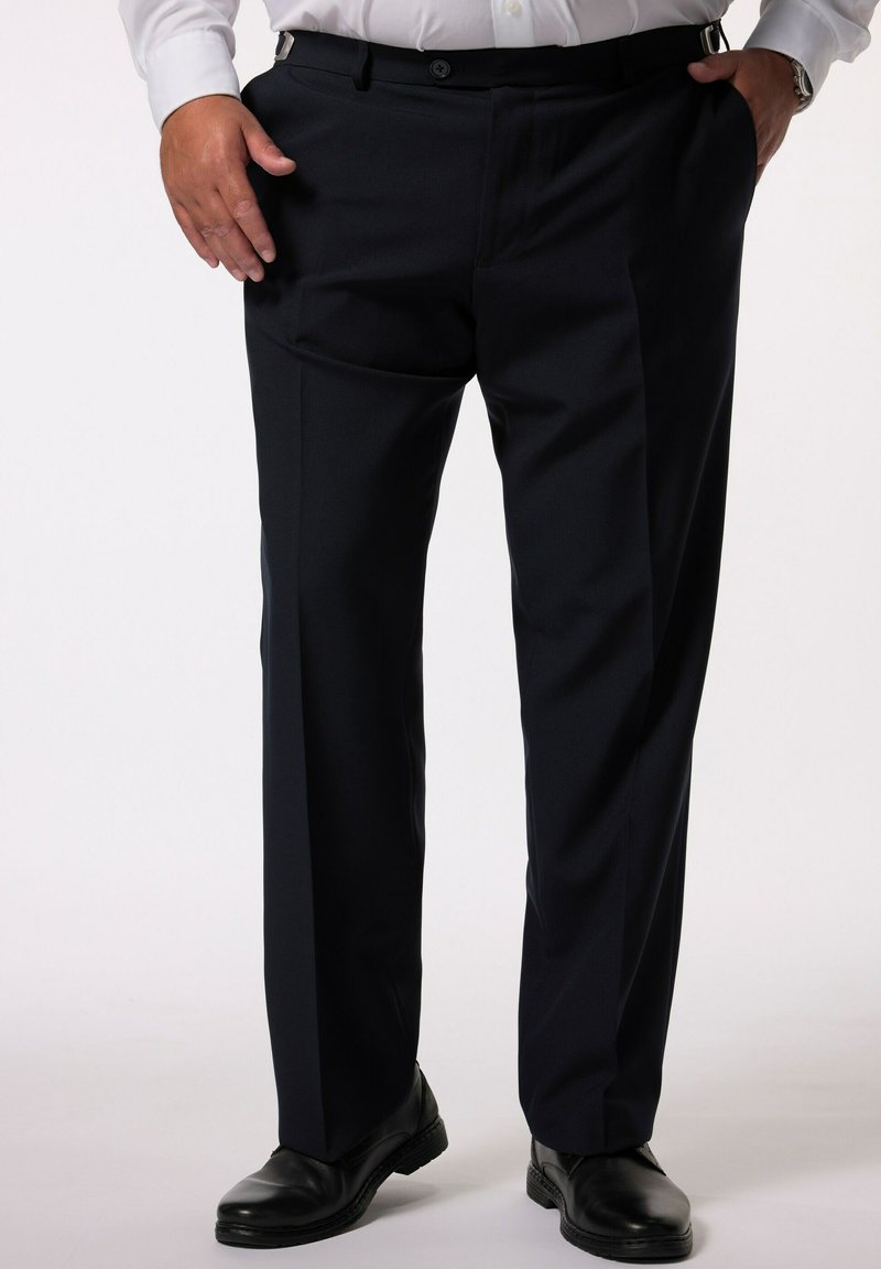 Pantaloni blu marine scuri con una texture liscia, vestibilità su misura e tasche frontali, abbinati a scarpe nere. Presentano una chiusura con bottone e cerniera.