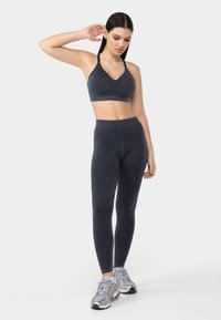 Soutien-gorge de sport gris foncé et leggings taille haute assortis en matériau extensible, présentant une texture lisse et un design simple.