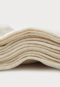 Φυσικές βαμβακερές κάλτσες στοιβαγμένες οριζόντια, με μαλακή υφή και κρεμ χρώμα, με ορατές ραβδώσεις στις πλευρές.