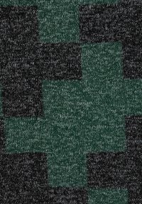 Stickad tyg med ett stort grönt korsmönster mot en mörk, fläckig bakgrund.