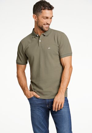 Olijfgroene poloshirt van gestructureerde stof, met een twee-knopsluiting en een subtiele logo op de linkerkant van de borst, gecombineerd met blauwe jeans.