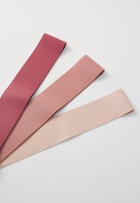Three elastic resistance bands in varying shades: dark burgundy, muted rose, and light peach. Each band is smooth and flat in design.
