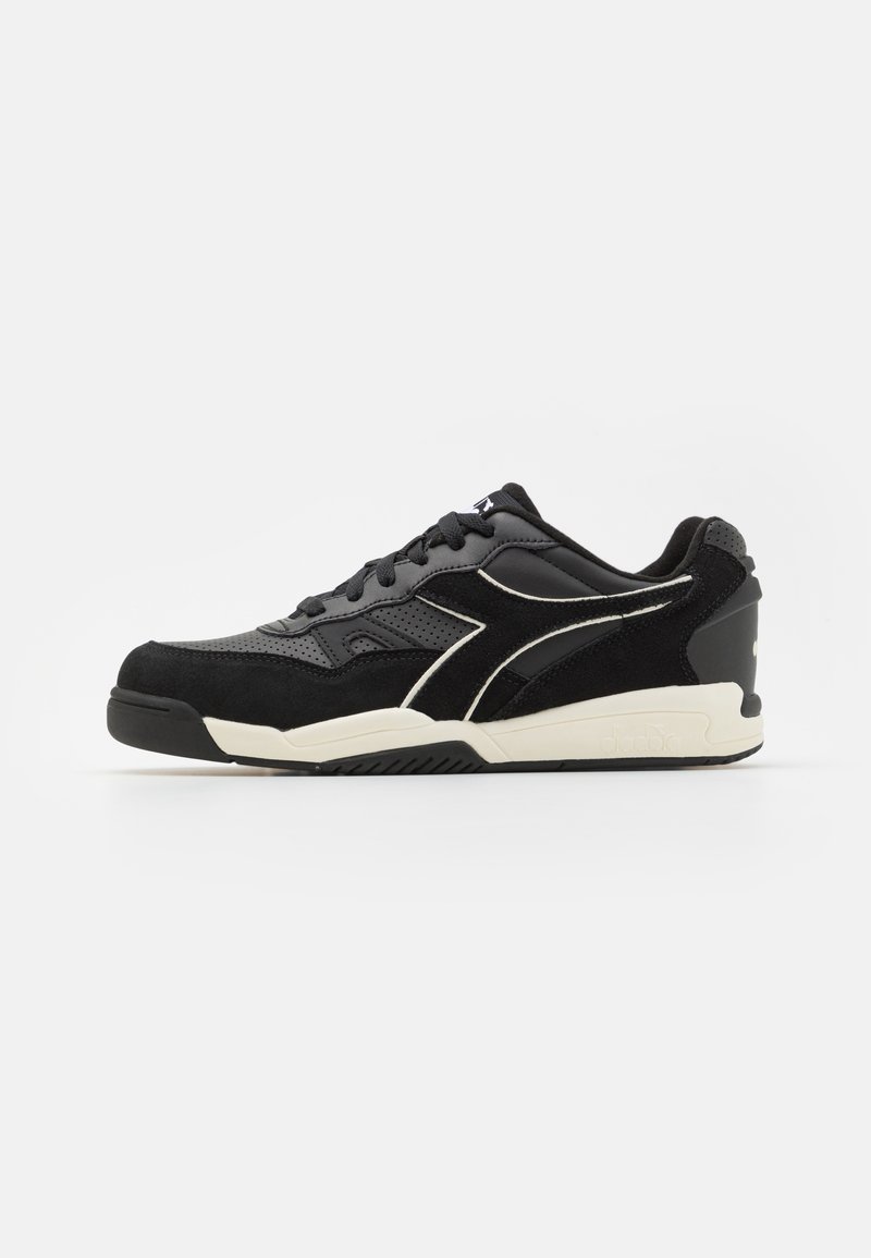 Black athletic shoe with a fabric upper featuring suede accents. Contrasting white detailing along the side and a textured rubber sole.